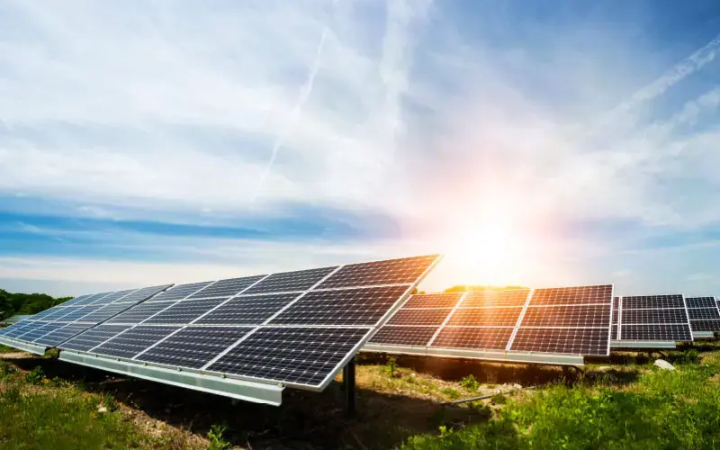 Paneles solares instalados en un campo verde, capturando la luz del sol bajo un cielo parcialmente despejado.