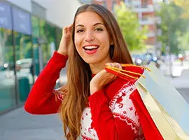 Mujer sonriente con suéter rojo y bolsas de compras en la calle