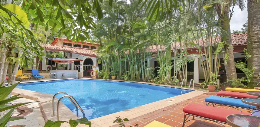 Piscina rodeada de vegetación tropical, sillas coloridas y arquitectura rústica en el Hotel Villas Lirio Manuel Antonio