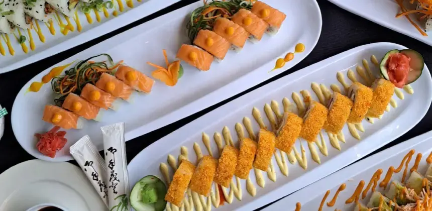 Platos de sushi variados servidos en bandejas blancas con presentación gourmet