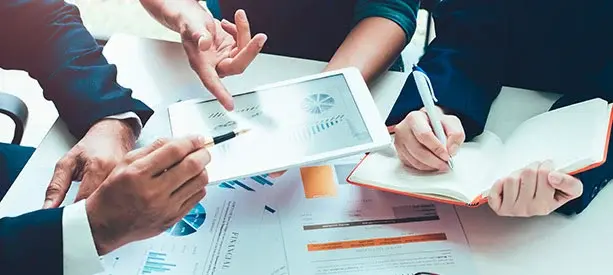 Personas revisando reportes financieros y gráficos en una reunión de negocios.