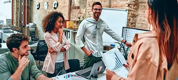 Grupo de jóvenes en una oficina colaborando en un proyecto con gráficas de crecimiento.