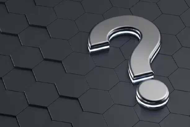 Signo de interrogación metálico sobre una superficie de hexágonos oscuros, con efecto de luz reflejada.