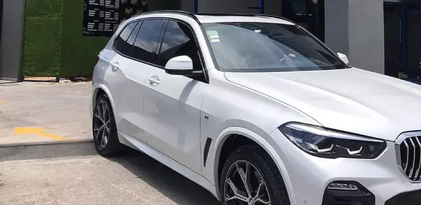 Automóvil SUV blanco estacionado en taller con detalles en negro y rines deportivos