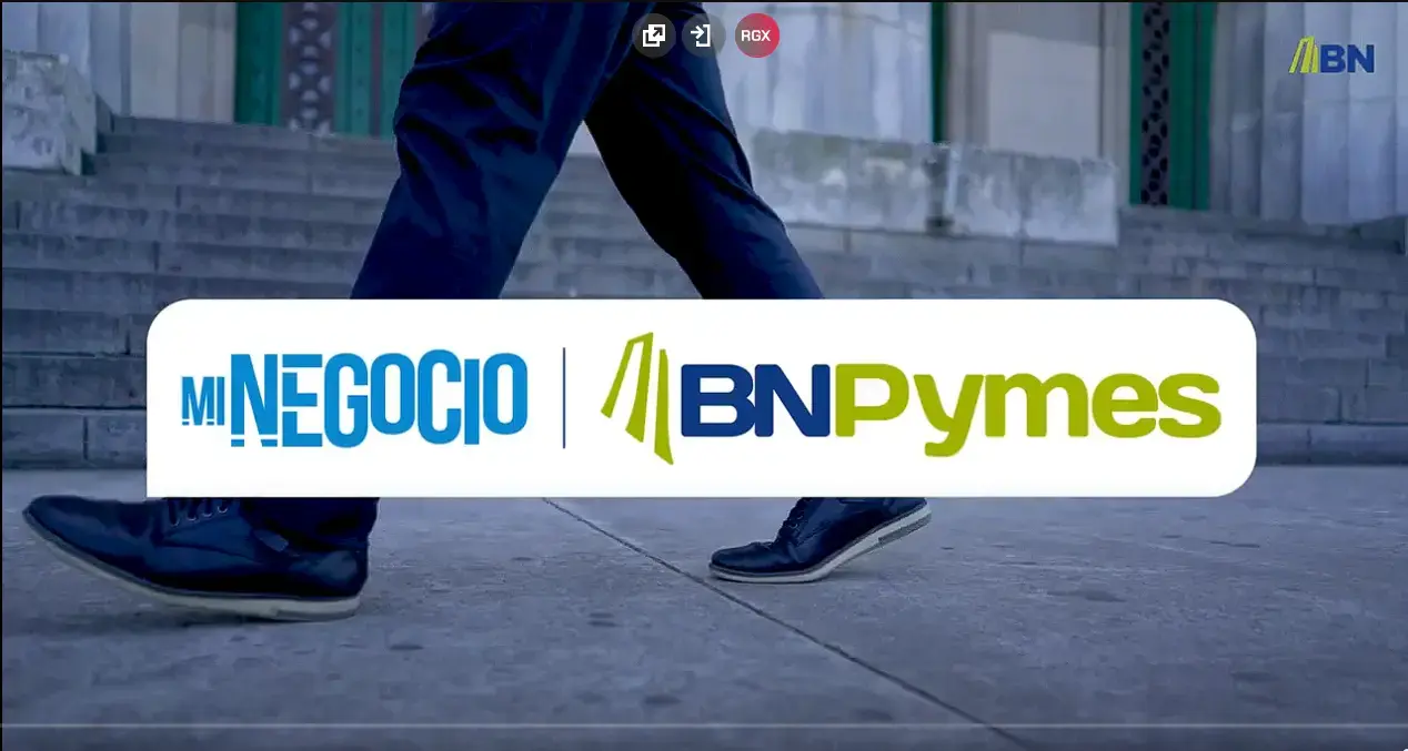 Persona caminando frente a unas escaleras de concreto, con un cartel superpuesto que muestra los logotipos de “Mi Negocio” y “BN Pymes” del Banco Nacional de Costa Rica.