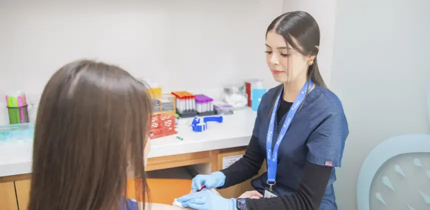 Profesional de laboratorio toma muestra de sangre a una paciente en sala clínica moderna