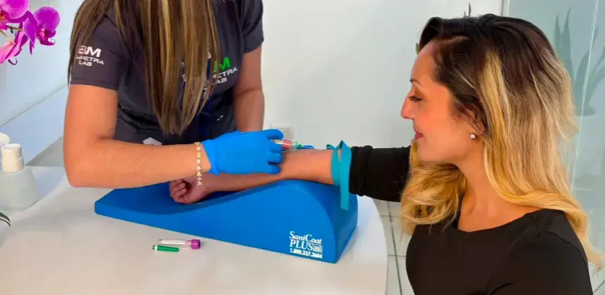 Toma de muestra de sangre realizada por técnica de laboratorio con guantes azules en brazo de paciente