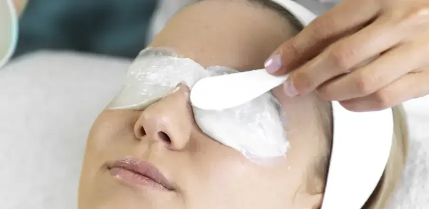 Persona recibiendo tratamiento facial con mascarilla blanca aplicada sobre los ojos en un centro estético