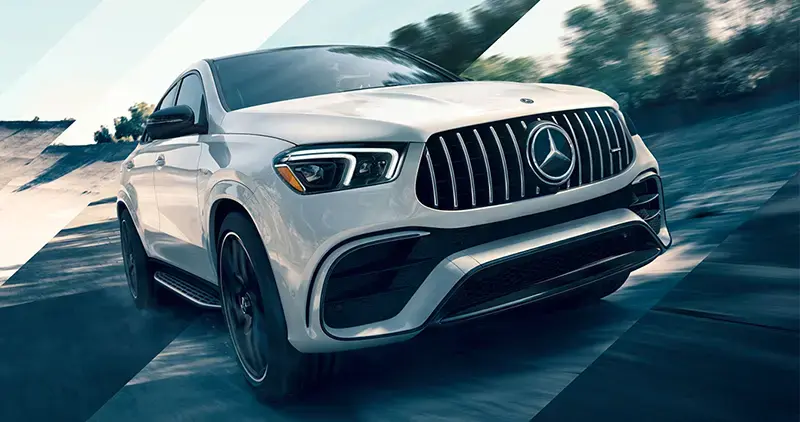 Vehículo Mercedes-Benz blanco circulando por una vía asfaltada en dirección diagonal.