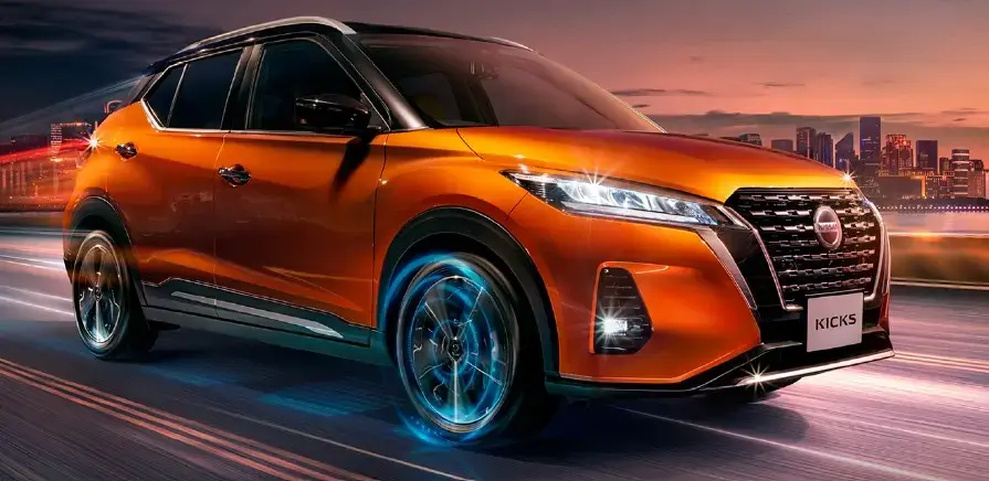 Vehículo Nissan Kicks en color naranja circulando en ciudad al atardecer, representando movilidad urbana y diseño moderno.