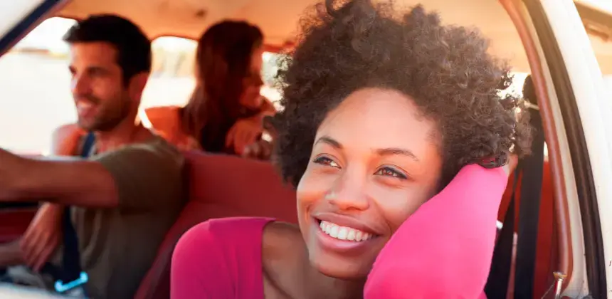 Personas sonriendo dentro de un auto durante un viaje por carretera en un día soleado